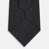 View 3 of product The Turnbull & Asser Teal and Navy Circle Silk Tie features a subtle herringbone pattern with small repeating circle motifs, displayed neatly rolled on a white background.