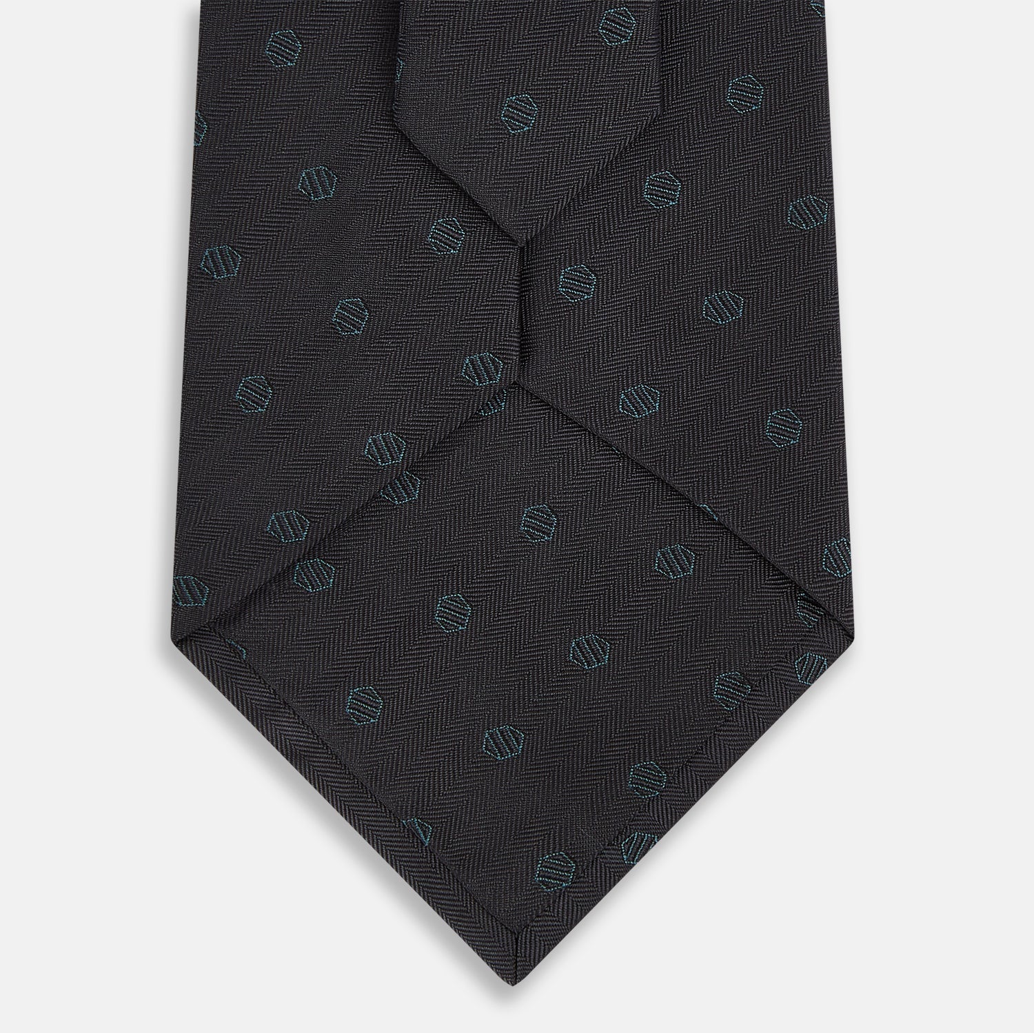 View 3 of product The Turnbull & Asser Teal and Navy Circle Silk Tie features a subtle herringbone pattern with small repeating circle motifs, displayed neatly rolled on a white background.