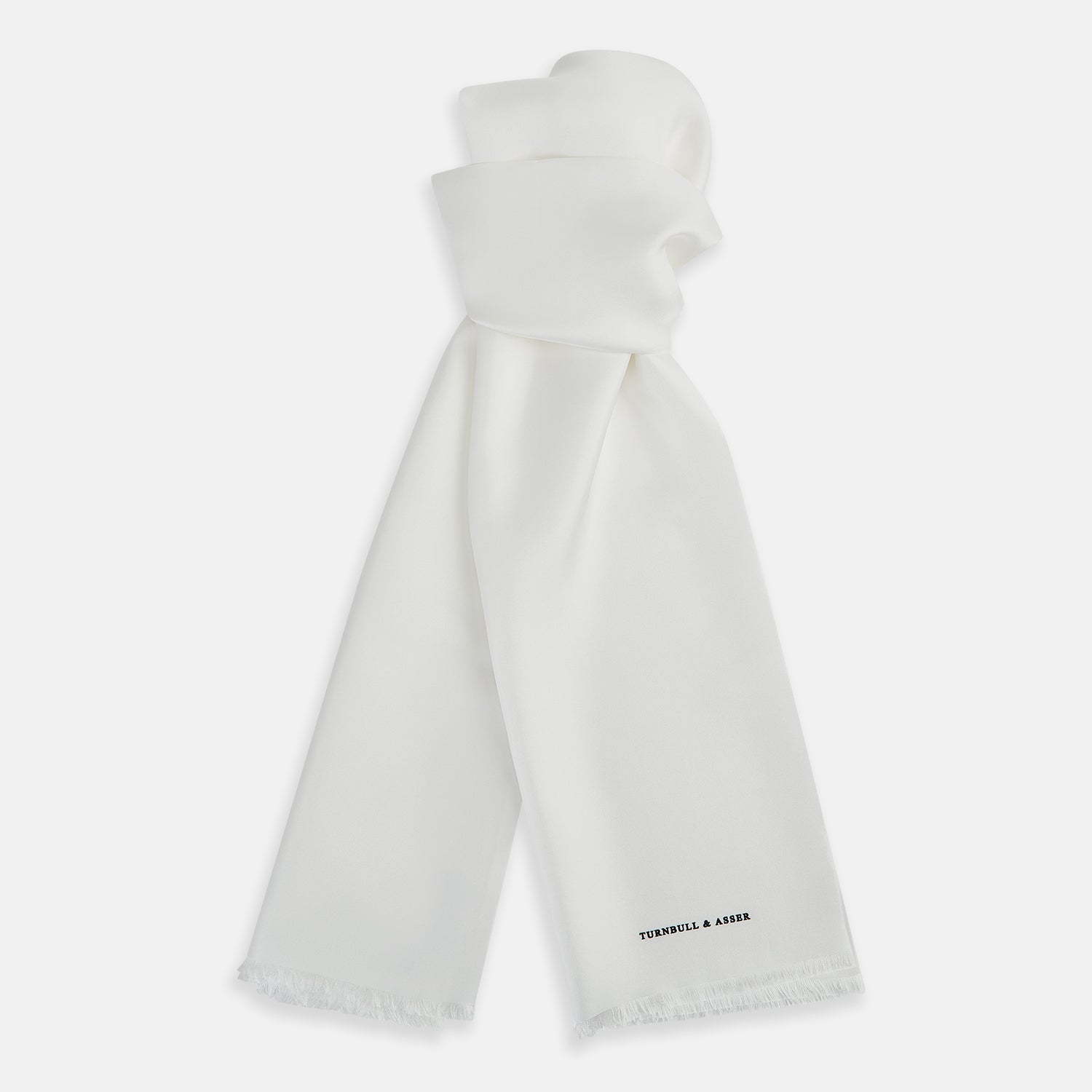 View 1 of product The Turnbull & Asser White Silk Scarf features fringed edges and discreet black branding in the corner, making it a refined accessory for tuxedo jackets or formal wear. Presented neatly folded on a plain white background.