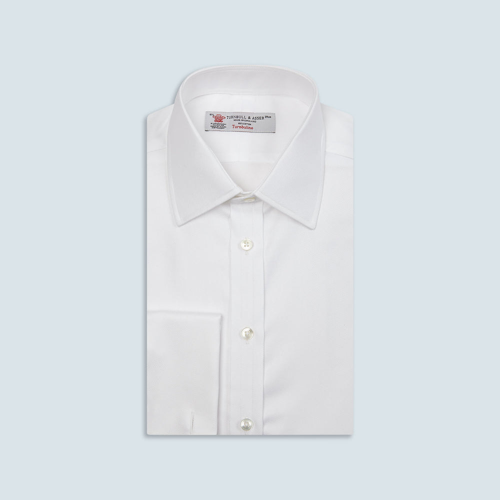 A neatly folded Turnbull & Asser White Oxford Shirt with T&A collar and double cuffs is displayed on a light blue background.