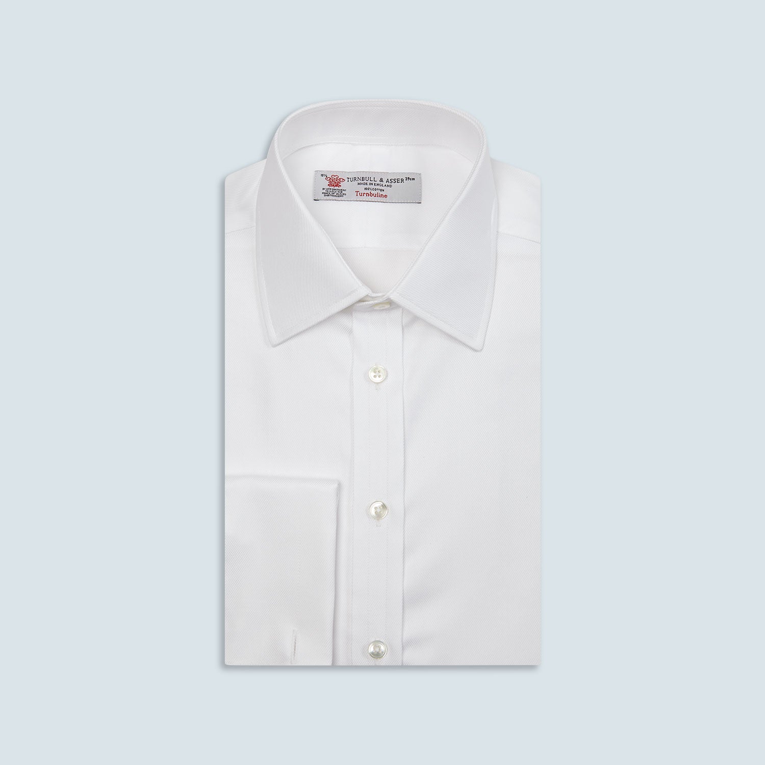 View 1 of product A neatly folded Turnbull & Asser White Oxford Shirt with T&A collar and double cuffs is displayed on a light blue background.