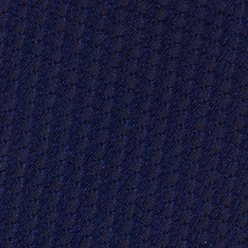 The Turnbull & Asser Seven-Fold Navy Lace Silk Tie is shown on a white background, rolled at one end with the pointed tip facing forward.