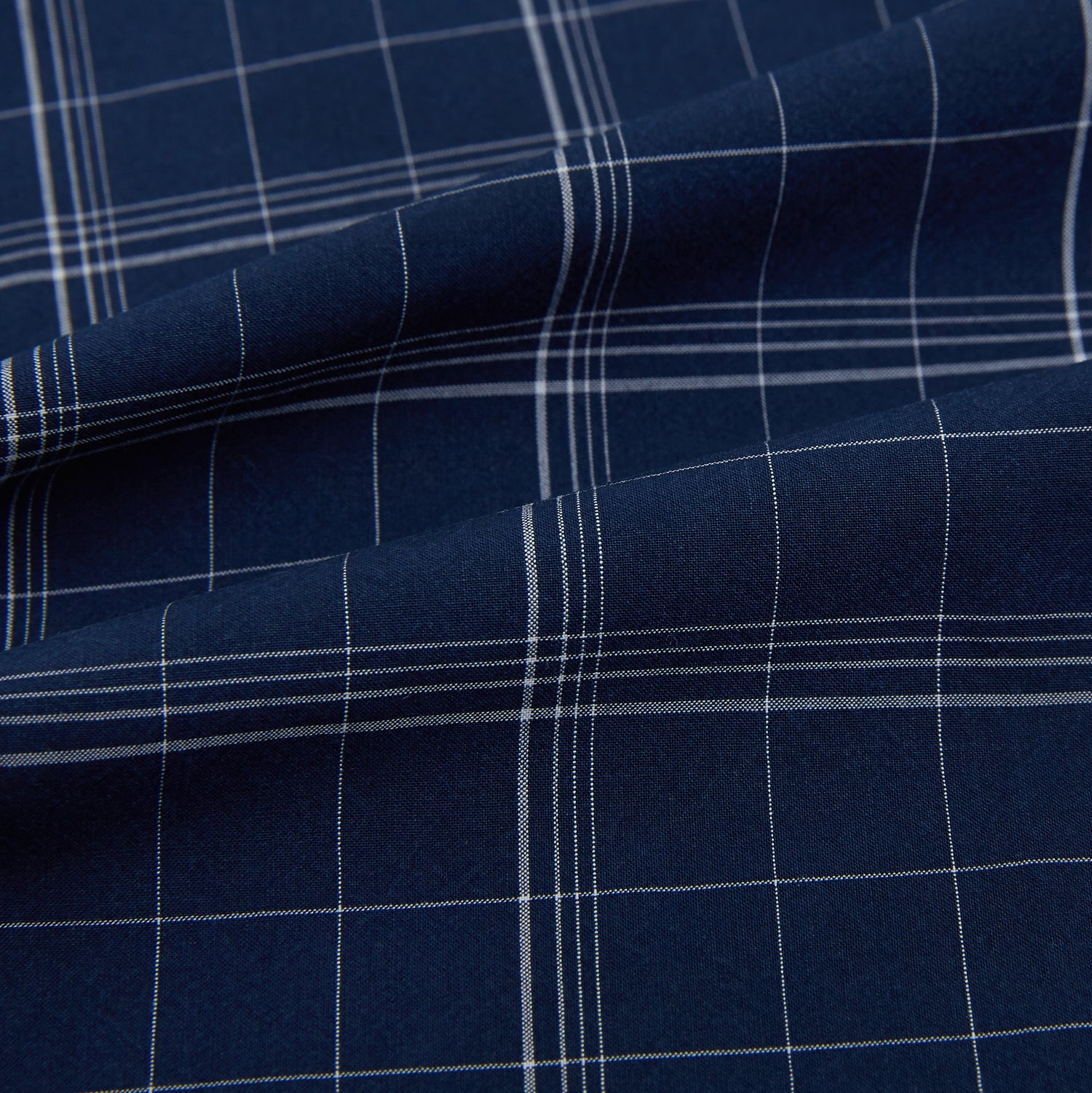 View 8 of product The Indigo and White Thin Plaid Check Windsor Shirt by Turnbull & Asser, a long-sleeve button-up with white buttons, is shown laid flat on a white background.