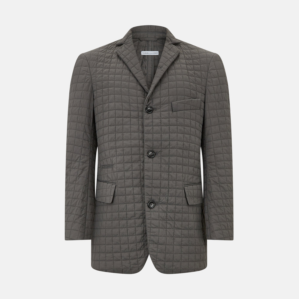 The Fulham Shadow Grey Single-Breasted Quilted Blazer by Turnbull & Asser features a checkered pattern, notched lapel, three front buttons, chest pocket, and two flap pockets—ideal for formal wear on a plain white background.