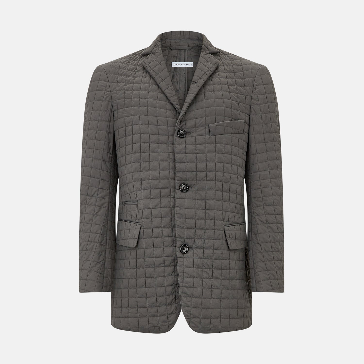 View 1 of product The Fulham Shadow Grey Single-Breasted Quilted Blazer by Turnbull & Asser features a checkered pattern, notched lapel, three front buttons, chest pocket, and two flap pockets—ideal for formal wear on a plain white background.