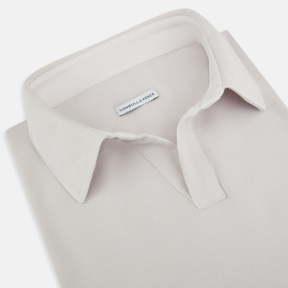 A pale pink luxury cotton rugby polo shirt by Turnbull & Asser, featuring long sleeves and a collar with no buttons, displayed flat on a white background.