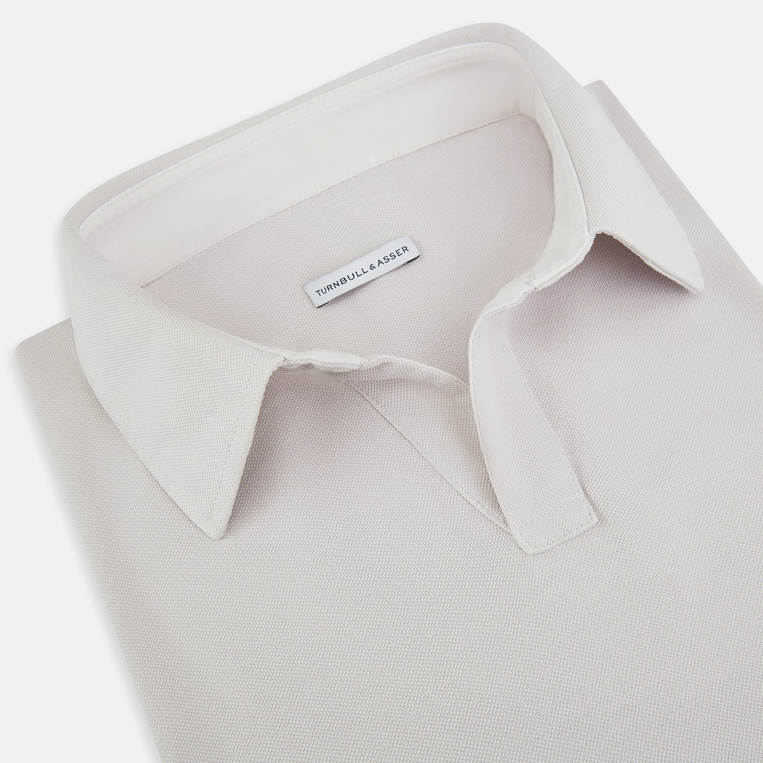 View 2 of product A pale pink luxury cotton rugby polo shirt by Turnbull & Asser, featuring long sleeves and a collar with no buttons, displayed flat on a white background.