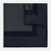 View 1 of product The Turnbull & Asser Navy and White Dot Silk Pocket Square features evenly spaced white polka dots on navy, a solid navy border, and one folded corner to reveal the reverse side, highlighting its fine handmade craftsmanship.