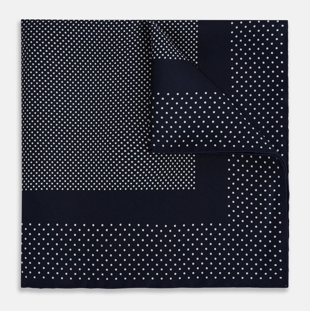 The Turnbull & Asser Navy and White Dot Silk Pocket Square features evenly spaced white polka dots on navy, a solid navy border, and one folded corner to reveal the reverse side, highlighting its fine handmade craftsmanship.