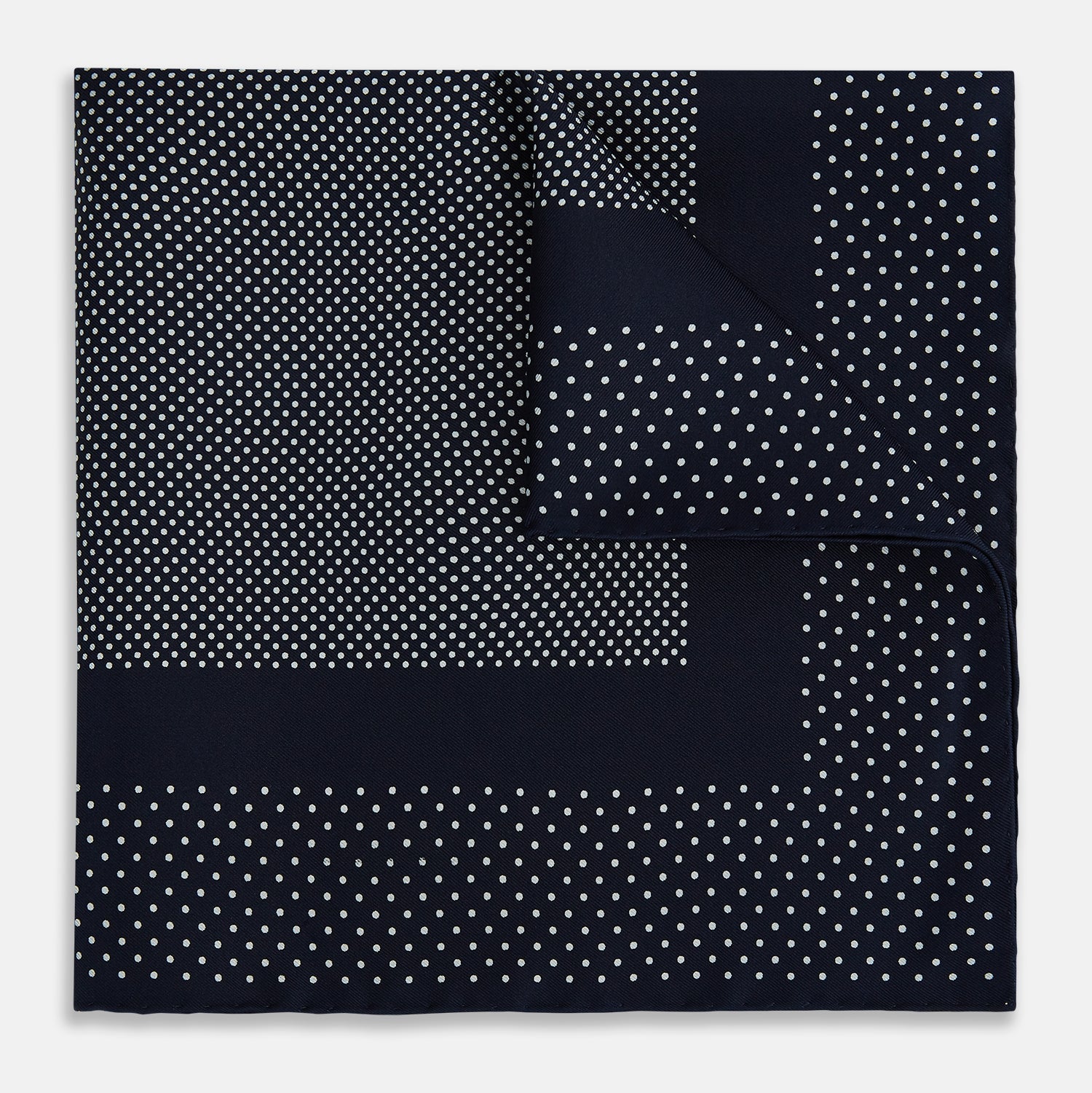 View 1 of product The Turnbull & Asser Navy and White Dot Silk Pocket Square features evenly spaced white polka dots on navy, a solid navy border, and one folded corner to reveal the reverse side, highlighting its fine handmade craftsmanship.