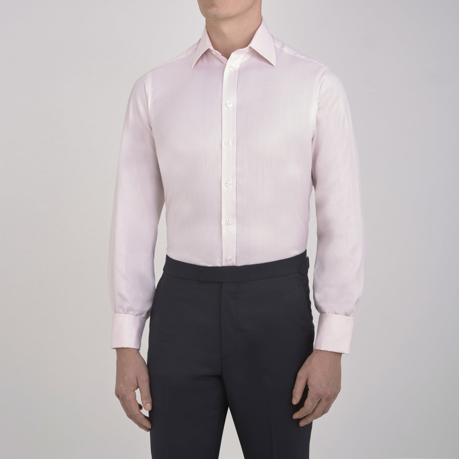 View 2 of product The Turnbull & Asser Pink Herringbone Superfine Cotton Shirt features a T&A collar, double cuffs, and clean-cut design, displayed neatly folded against a white background.
