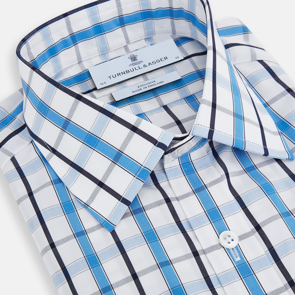 The Turnbull & Asser Blue and Navy Combination Check Mayfair Shirt features a classic button-up style with long sleeves, T&A collar, and a blue, navy, and white check pattern, shown against a plain white background.