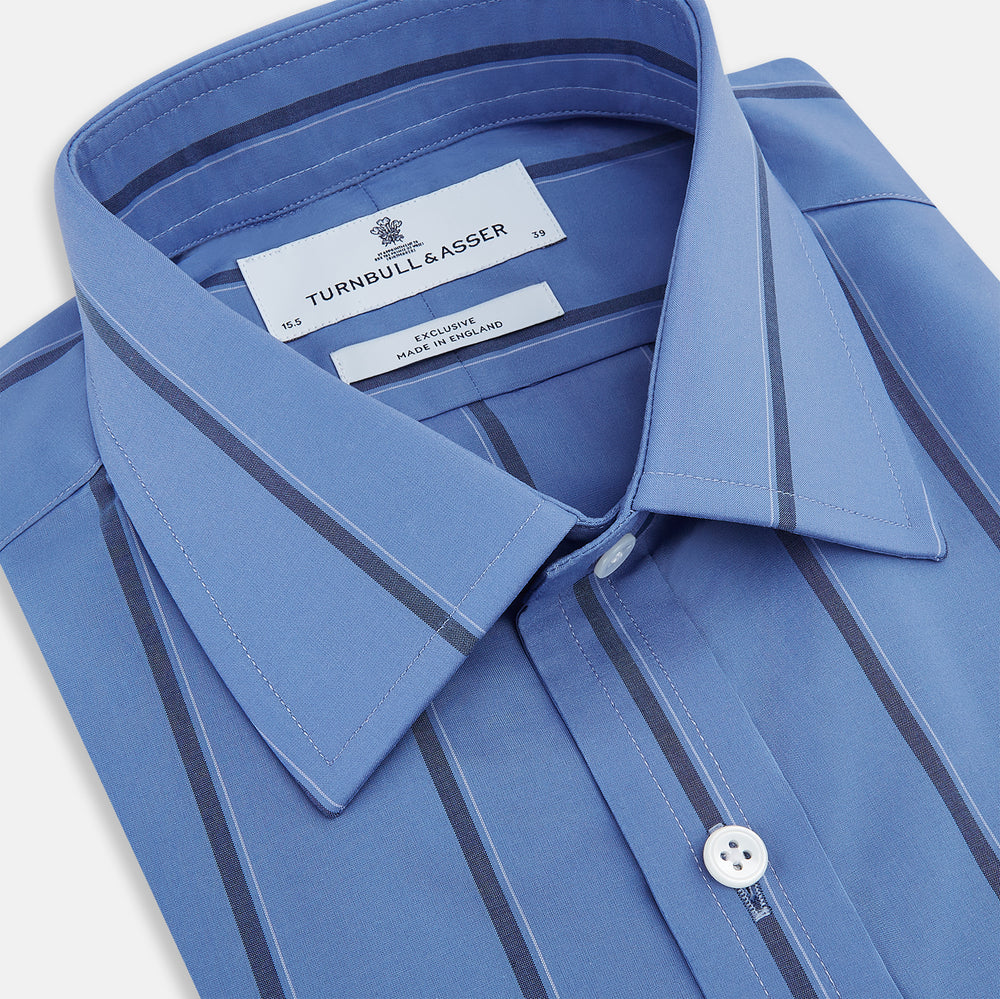 The Turnbull & Asser Colony Blue Track Stripe Mayfair Shirt is crafted from Italian cotton with long sleeves, dark blue track stripes, a classic collar, and buttoned cuffs, shown against a white background.