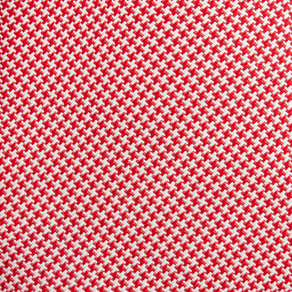 The Turnbull & Asser Red and White patterned silk tie, crafted from fine silk with a small geometric design, is elegantly rolled and displayed on a white background—a refined men’s accessory.