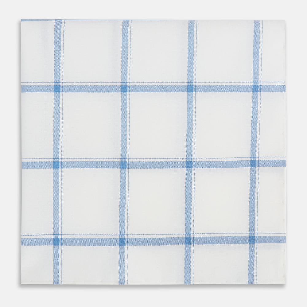 The Turnbull & Asser Colony Blue Grid Check Hand-Rolled Handkerchief features a white base with intersecting light and dark blue plaid lines forming squares, shown folded on a plain white background.