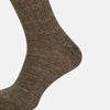 View 2 of product A single Dark Chocolate Linen Mid-Length Sock by Turnbull & Asser, ribbed and breathable, stands upright with its foot slightly raised against a plain white background.