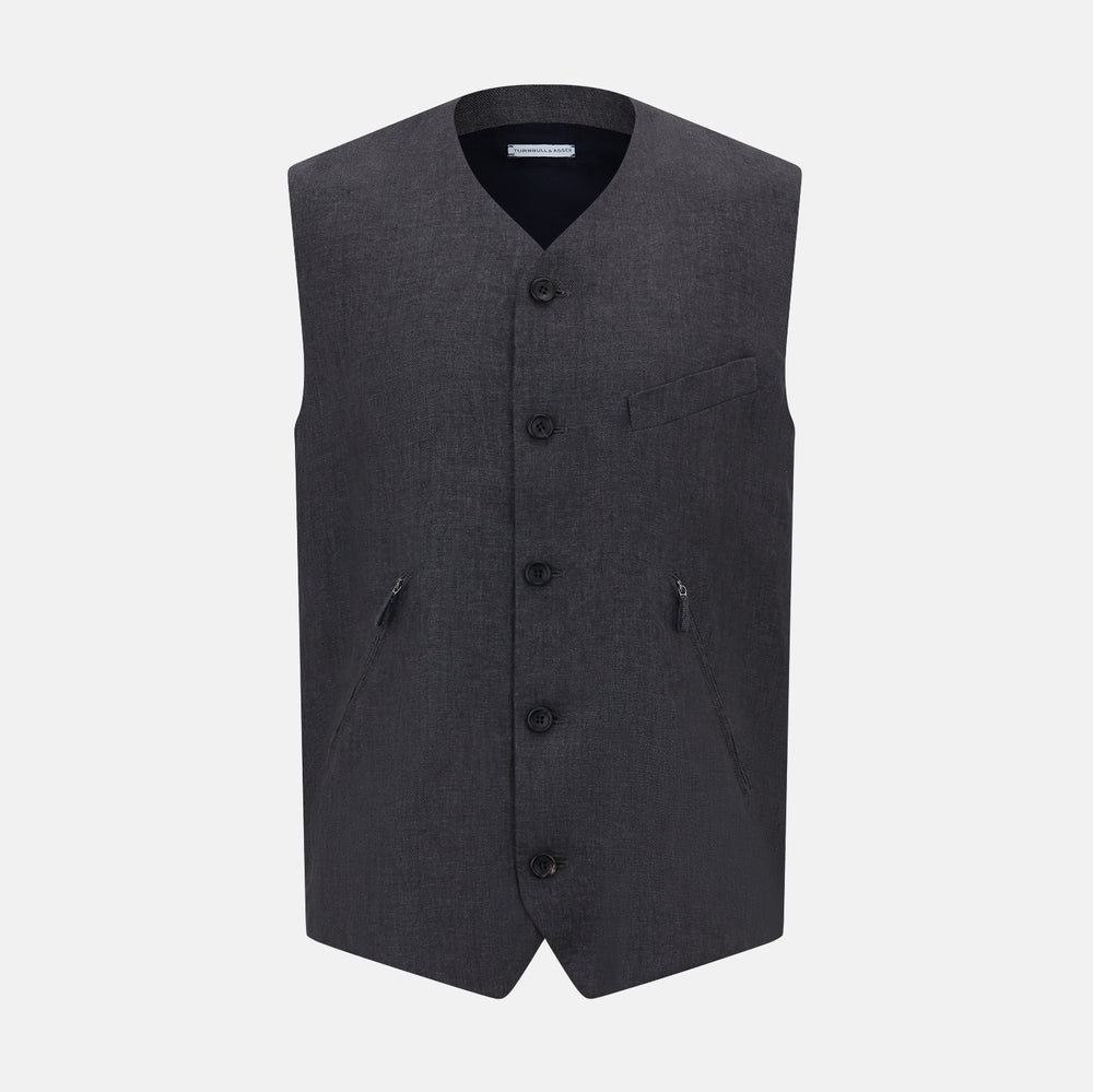 The Turnbull & Asser Ash Linen Twill Waistcoat is a dark gray, sleeveless V-neck with three front buttons, a chest pocket, and two diagonal zippered pockets in subtly textured twill. Shown on a plain white background.