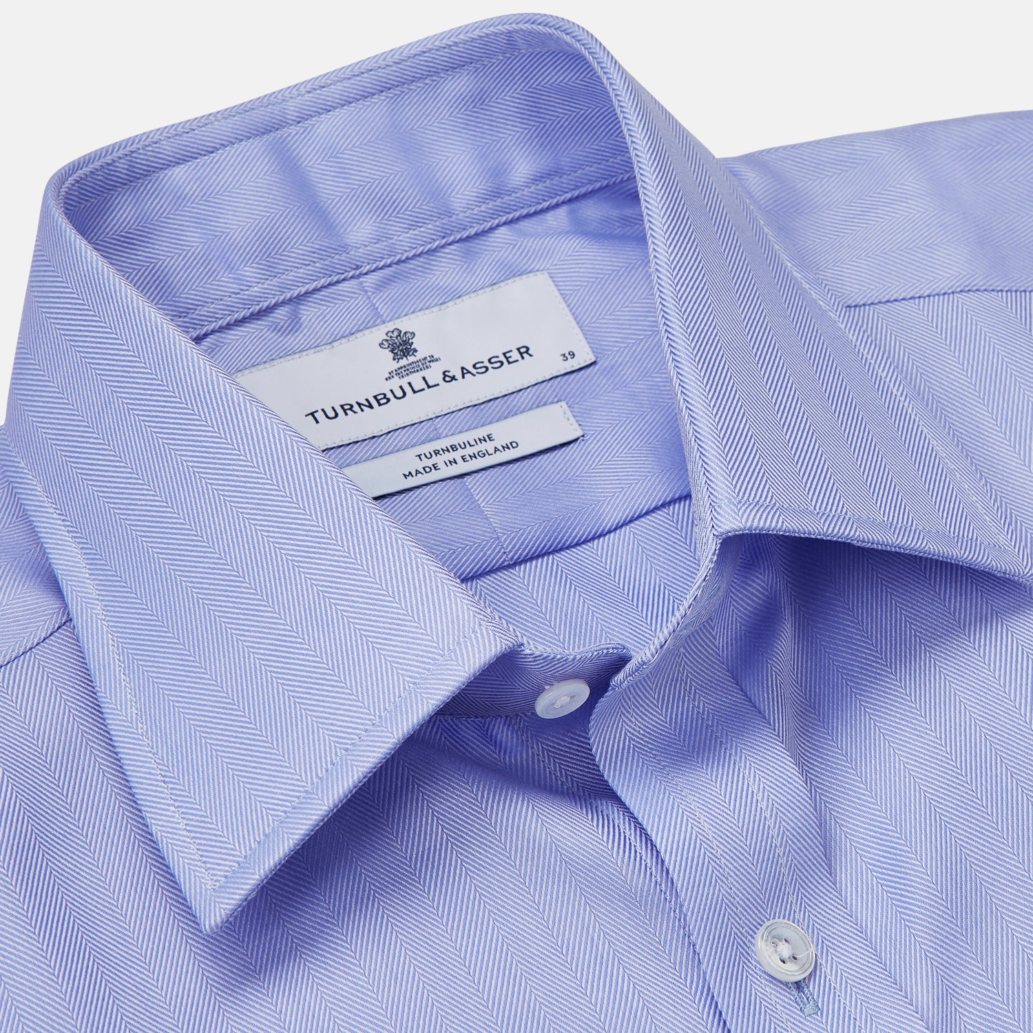 View 4 of product The Turnbull & Asser Blue Herringbone Regular Fit Shirt features a classic Kent collar, long sleeves, white buttons, and buttoned cuffs. Displayed on a white background, it's the perfect formal shirt for any occasion.