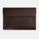 The Turnbull & Asser Burgundy Leather Snap-Fasten Pouch is a sleek, envelope-style laptop accessory with a smooth finish, curved flap, and elegant snap closure, ideal for business travel against a white background.