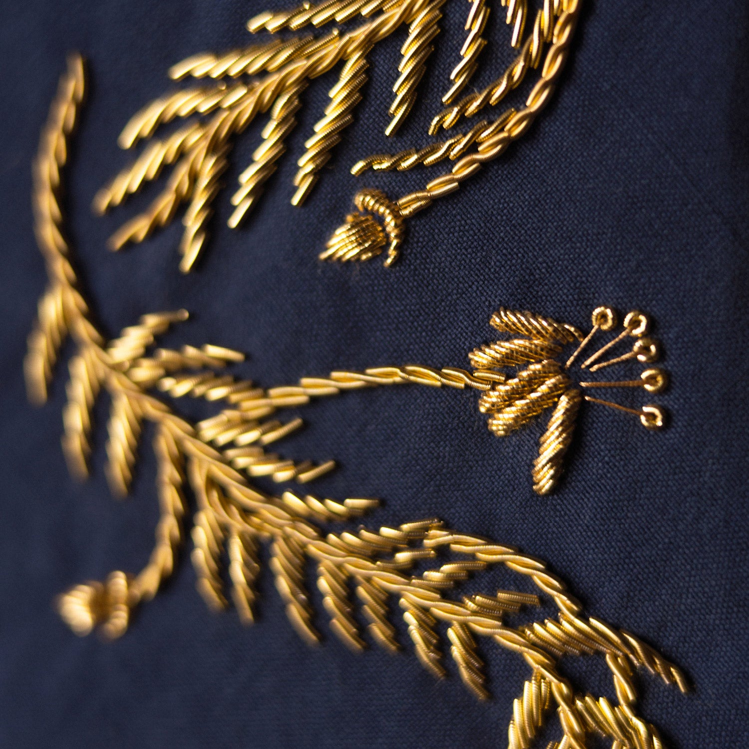 View 3 of product The Turnbull & Asser Navy Gold Embroidered Botanical Tie features intricate gold botanical embroidery on navy blue silk, neatly rolled with the detailed tip facing forward.