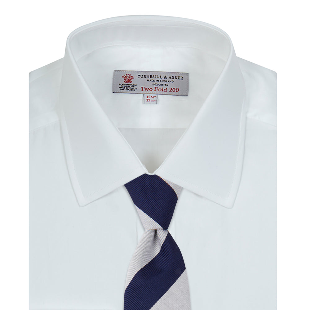 A Turnbull & Asser Two-Fold 200 White Cotton Shirt with T&A collar and double cuffs, neatly folded to show the label inside the collar, is displayed on a light blue background.