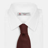 View 2 of product The Turnbull & Asser Dark Red Knitted Tie, featuring a textured finish, is shown rolled up against a white background—a stylish and versatile accessory ideal for the modern gentleman.