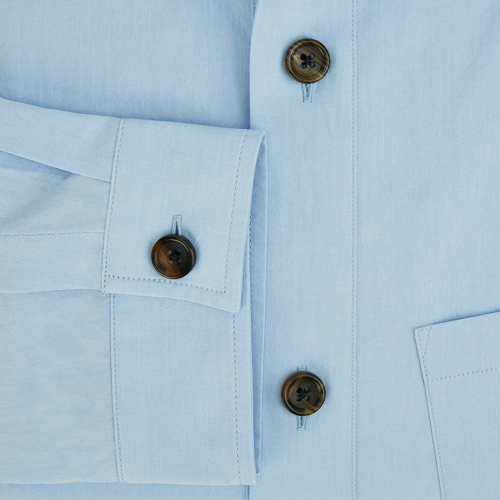 The Blue Hyde Overshirt by Turnbull & Asser features a light blue hue, long sleeves, a button-up front, and a single chest pocket. Crafted from sanforised cotton and shown laid flat on a white background.