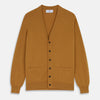 View 1 of product The Turnbull & Asser Golden Brown Cashmere Lachlan Cardigan features long sleeves, front buttons, two front pockets, and ribbed cuffs and hem—a luxurious knitwear piece shown laid flat on a white background.