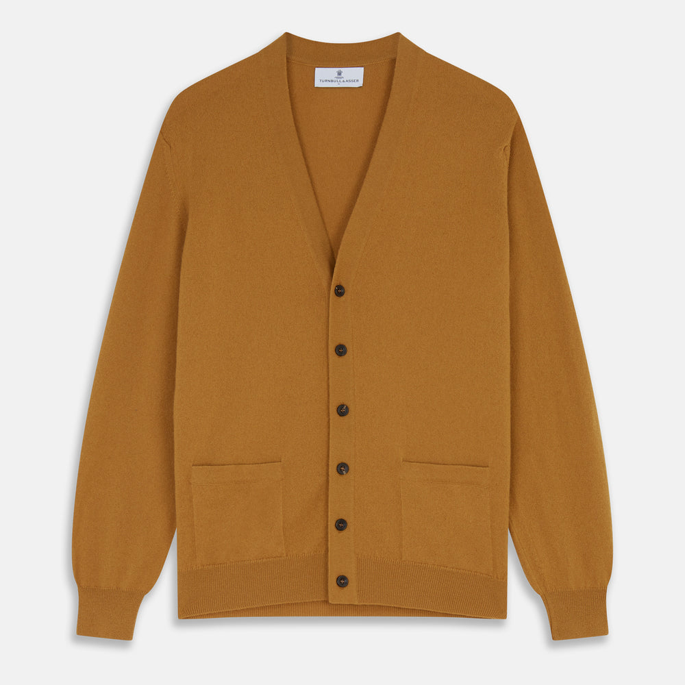 The Turnbull & Asser Golden Brown Cashmere Lachlan Cardigan features long sleeves, front buttons, two front pockets, and ribbed cuffs and hem—a luxurious knitwear piece shown laid flat on a white background.