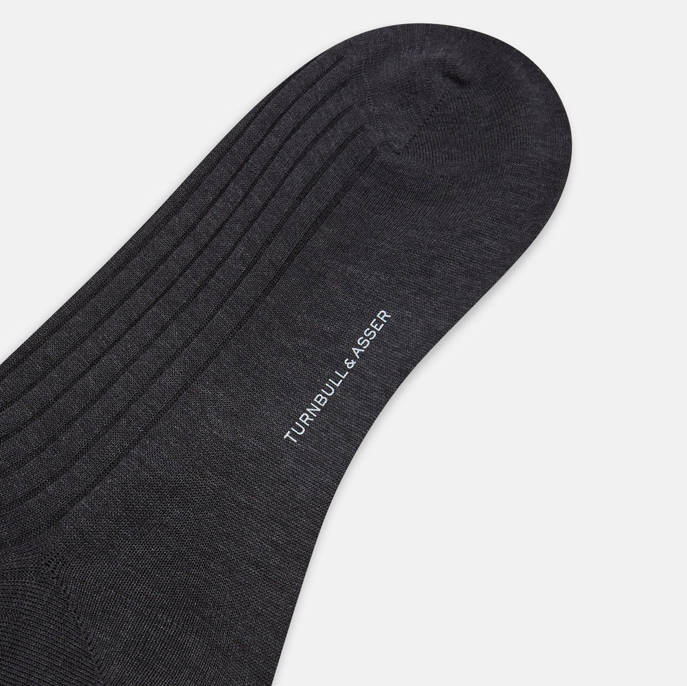 A single Turnbull & Asser Charcoal Long Sock, crafted from mercerised Egyptian cotton with a ribbed texture, is shown on a plain white background, positioned as if worn with the heel slightly raised.