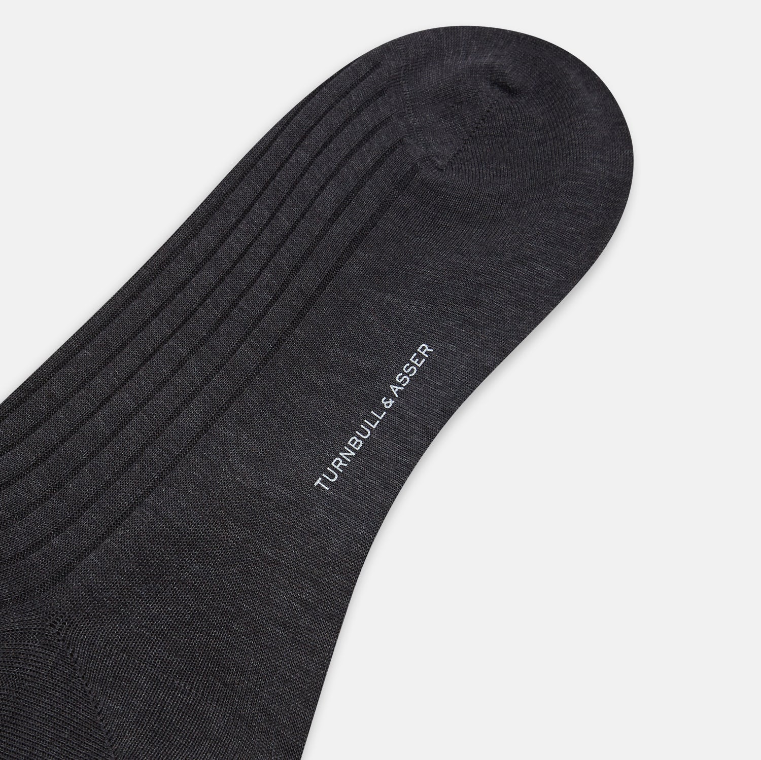 View 3 of product A single Turnbull & Asser Charcoal Long Sock, crafted from mercerised Egyptian cotton with a ribbed texture, is shown on a plain white background, positioned as if worn with the heel slightly raised.