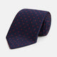 The Turnbull & Asser LACE ON TONE SPOT NAVY TULIP RED TIE is a classic men's accessory crafted from textured navy fabric with small red polka dots, neatly rolled with the pointed end facing forward.