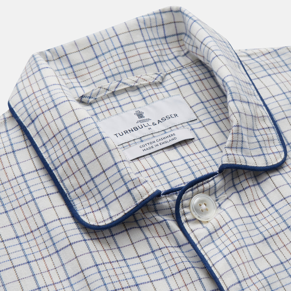 The Turnbull & Asser Blue Multi Check Cotton-Cashmere Modern Pyjama Set features a two-piece design with a long-sleeve button-up top with breast pocket and matching elastic-waist pants in a blue and white check pattern.