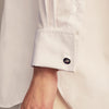 View 5 of product A woman with straight brown hair pulled back wears the Turnbull & Asser White Cotton Marlene Shirt, featuring classic menswear details, paired with high-waisted cream trousers against a neutral background.