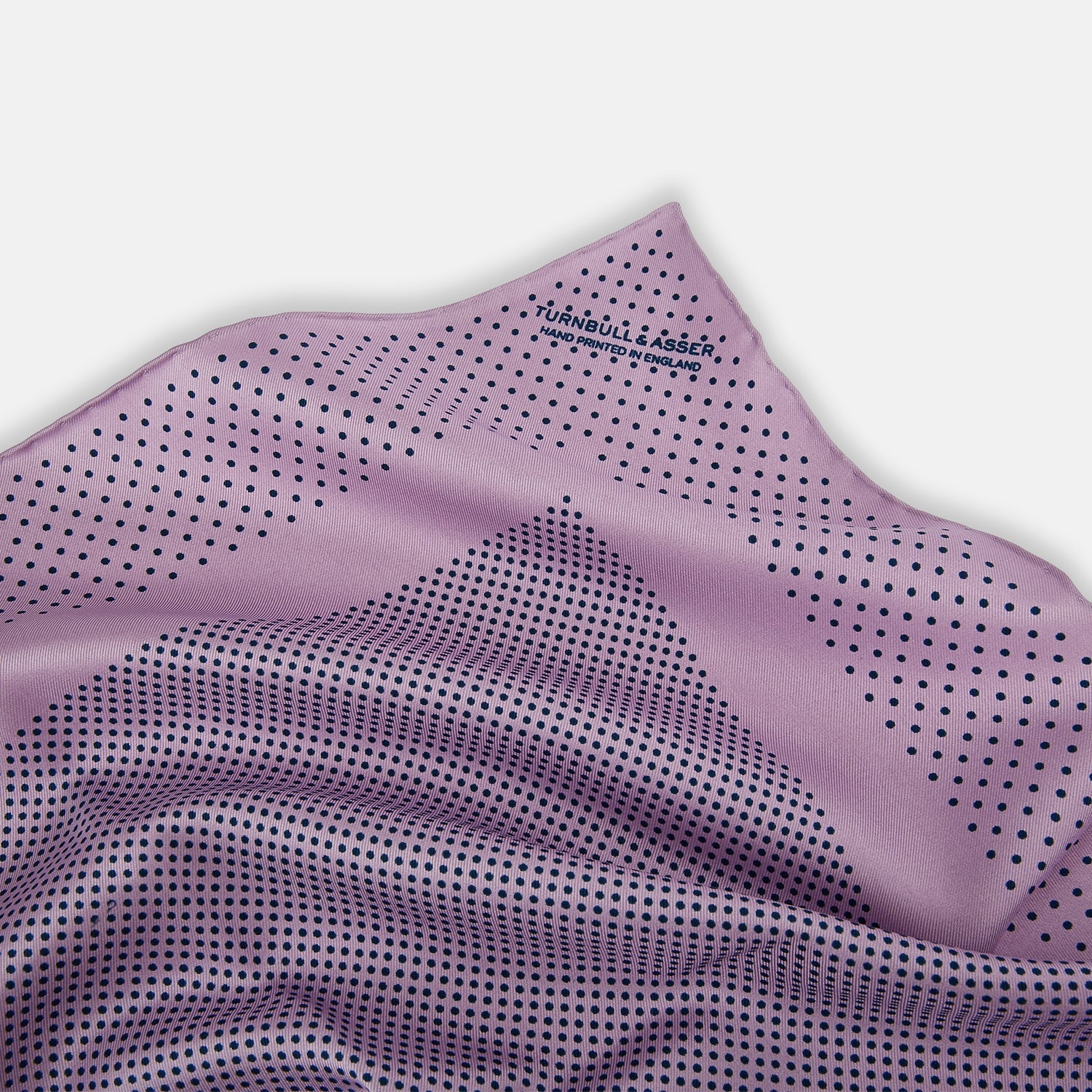 View 2 of product The Lilac Dot Silk Pocket Square by Turnbull & Asser is handmade from silk in a folded design, featuring small black polka dots and a solid border.