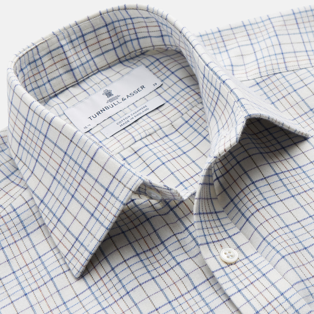 The Turnbull & Asser Blue Multi Check Regular Fit Cotton-Cashmere Shirt features a T&A collar, 3 button cuffs, and a white background with tonal blue and light brown checks—shown flat against a white background.