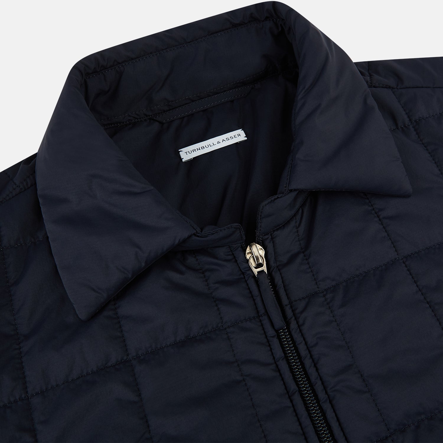View 2 of product The Turnbull & Asser Battersea Navy Quilted Jacket features a versatile quilted design with a front zipper, zippered pockets, collared neckline, buttoned cuffs, and a subtle square pattern—perfect for the modern gentleman.