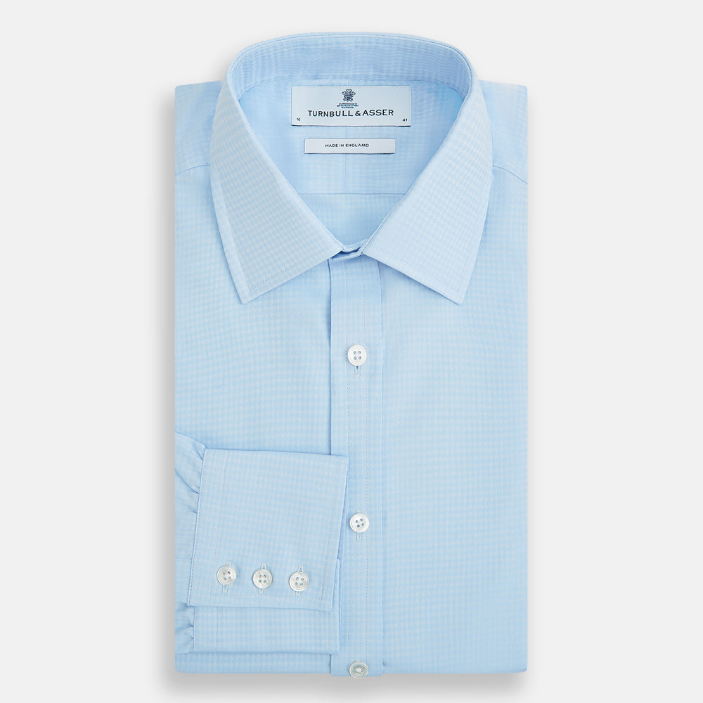 The Pale Blue Rhombus Mayfair Shirt by Turnbull & Asser features long sleeves, a classic collar, white buttons, and buttoned cuffs, shown laid flat on a white background.