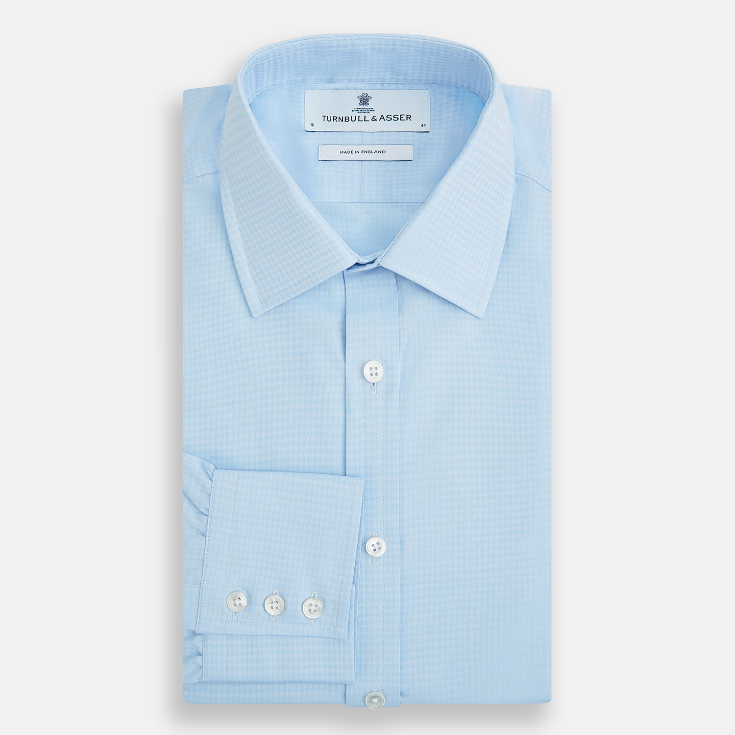 View 5 of product The Pale Blue Rhombus Mayfair Shirt by Turnbull & Asser features long sleeves, a classic collar, white buttons, and buttoned cuffs, shown laid flat on a white background.