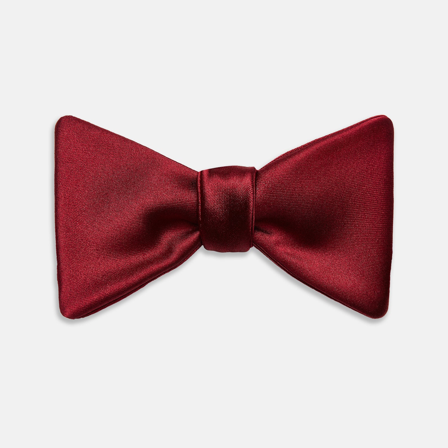 View 1 of product The Turnbull & Asser BURGUNDY SATIN BOW TIE features a deep red, smooth, and shiny finish—an essential accessory—neatly tied and showcased against a plain white background.