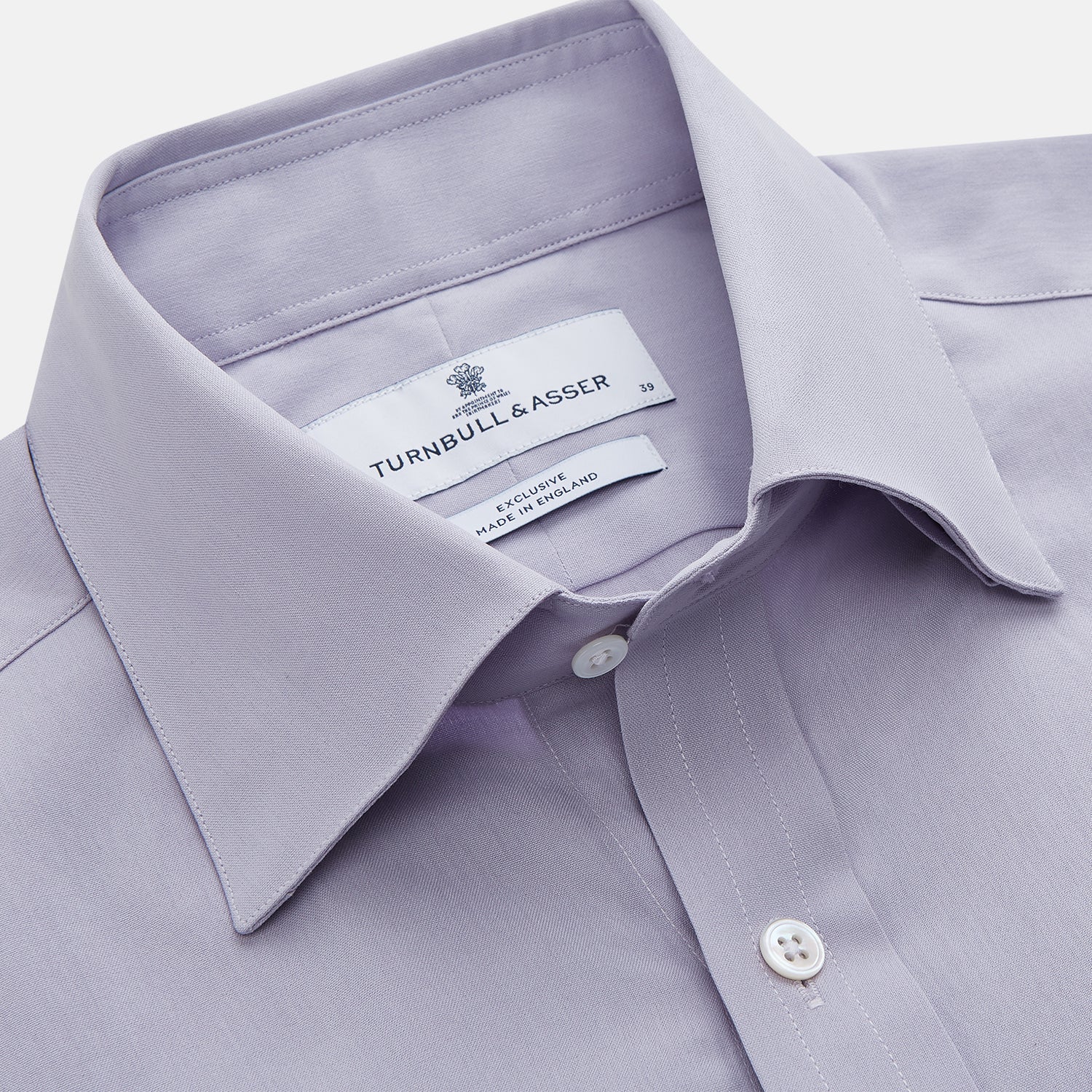 View 2 of product The Turnbull & Asser Lilac Silk Regular Fit Flaxton Shirt features long sleeves, a classic collar, white buttons, and a curved hem, shown laid flat on a white background.