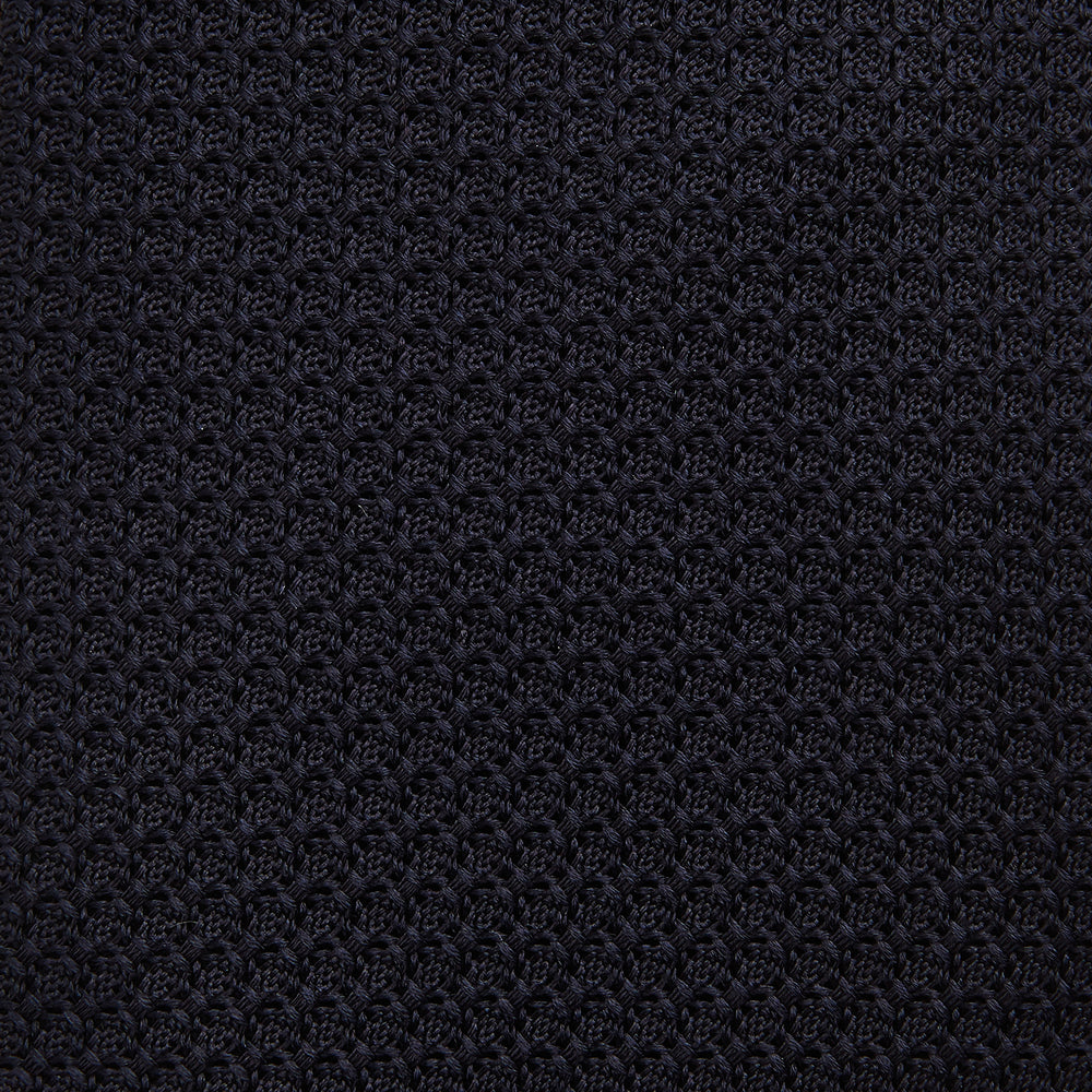 The GRENADINE NAVY TIE by Turnbull & Asser—a rolled, dark navy blue textured tie—serves as an essential accessory for smart outfits, shown against a plain white background.