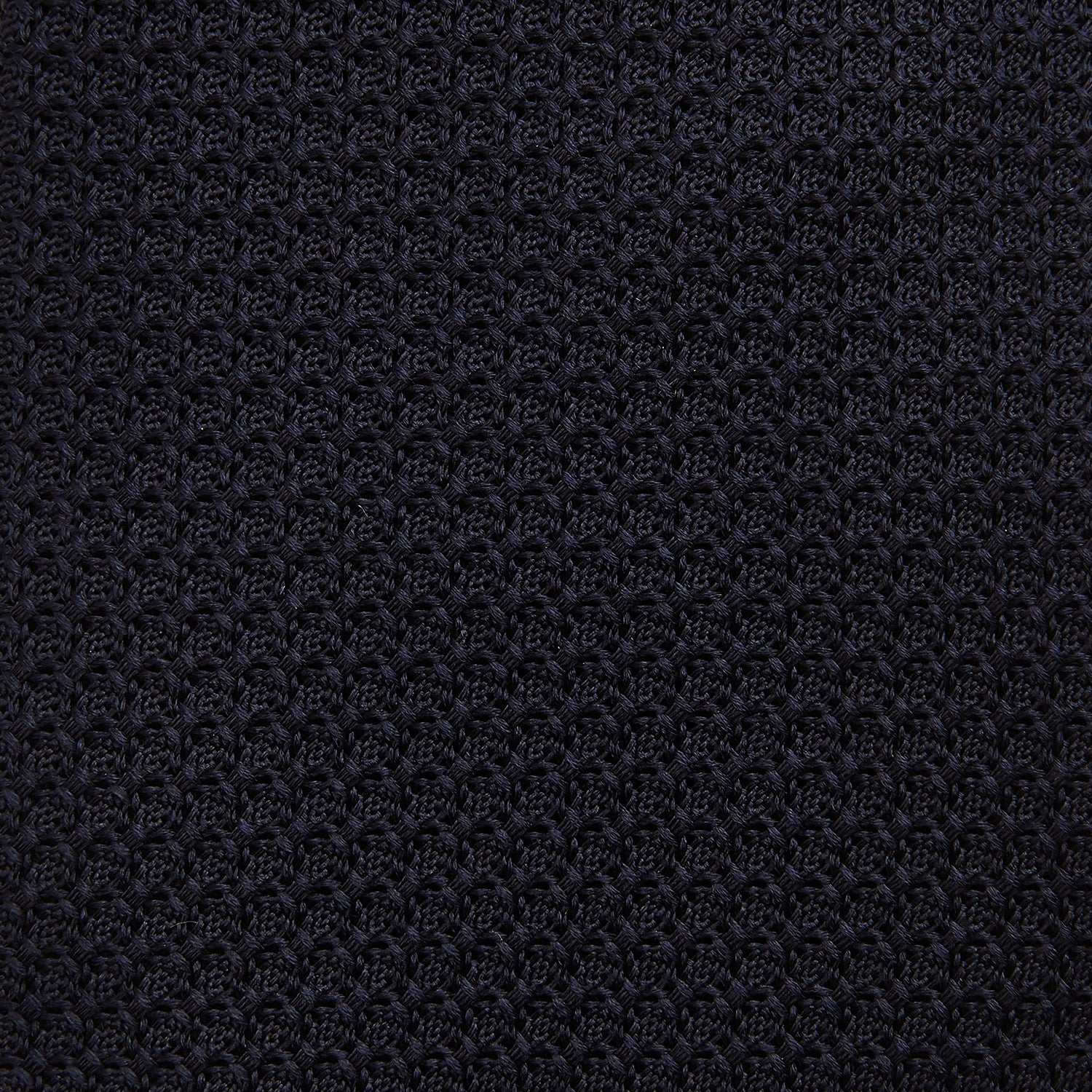 View 3 of product The GRENADINE NAVY TIE by Turnbull & Asser—a rolled, dark navy blue textured tie—serves as an essential accessory for smart outfits, shown against a plain white background.