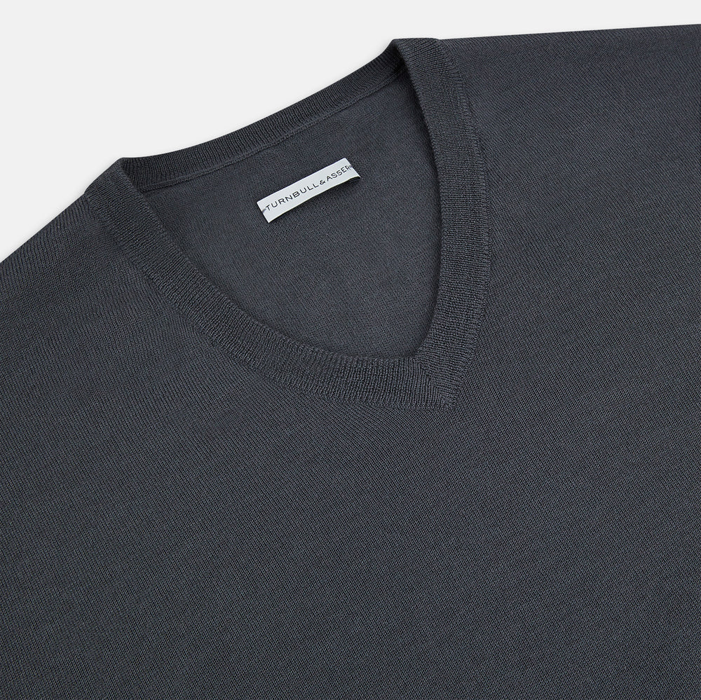 The Turnbull & Asser Charcoal Grey Merino V-Neck Jumper is shown against a white background, featuring long sleeves, a relaxed fit, and ribbed cuffs and hem for comfort.