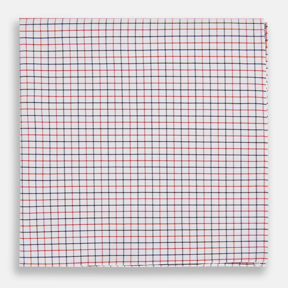Turnbull & Asser’s Hand Rolled Red and Navy Graph Check Handkerchief—a white cotton accessory with red and navy grid lines, neatly folded for a touch of refined elegance.