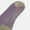 View 3 of product The Turnbull & Asser Concrete Houndstooth Mid-Length Sock features a purple and black houndstooth pattern with beige cuff, heel, and toe, crafted from soft cotton and shown on a plain white background.