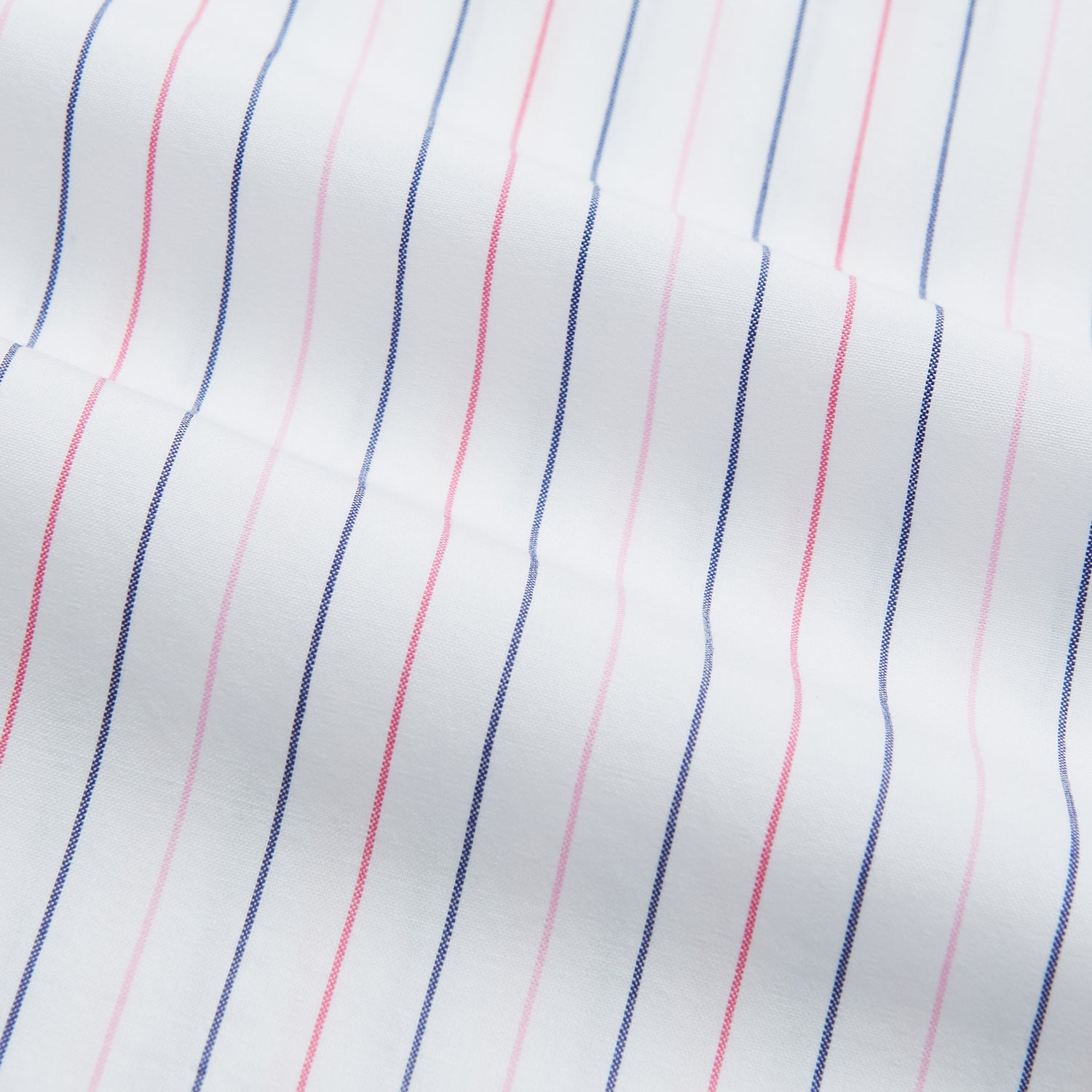 View 13 of product The Turnbull & Asser Pink and Blue Wide Pinstripe Mayfair Shirt features long sleeves, T&A collar, button-down front, and buttoned cuffs. It has bold pink and blue pinstripes on white and is laid flat on a white surface.
