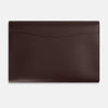 View 4 of product The Turnbull & Asser Burgundy Leather Snap-Fasten Pouch is a sleek, envelope-style laptop accessory with a smooth finish, curved flap, and elegant snap closure, ideal for business travel against a white background.