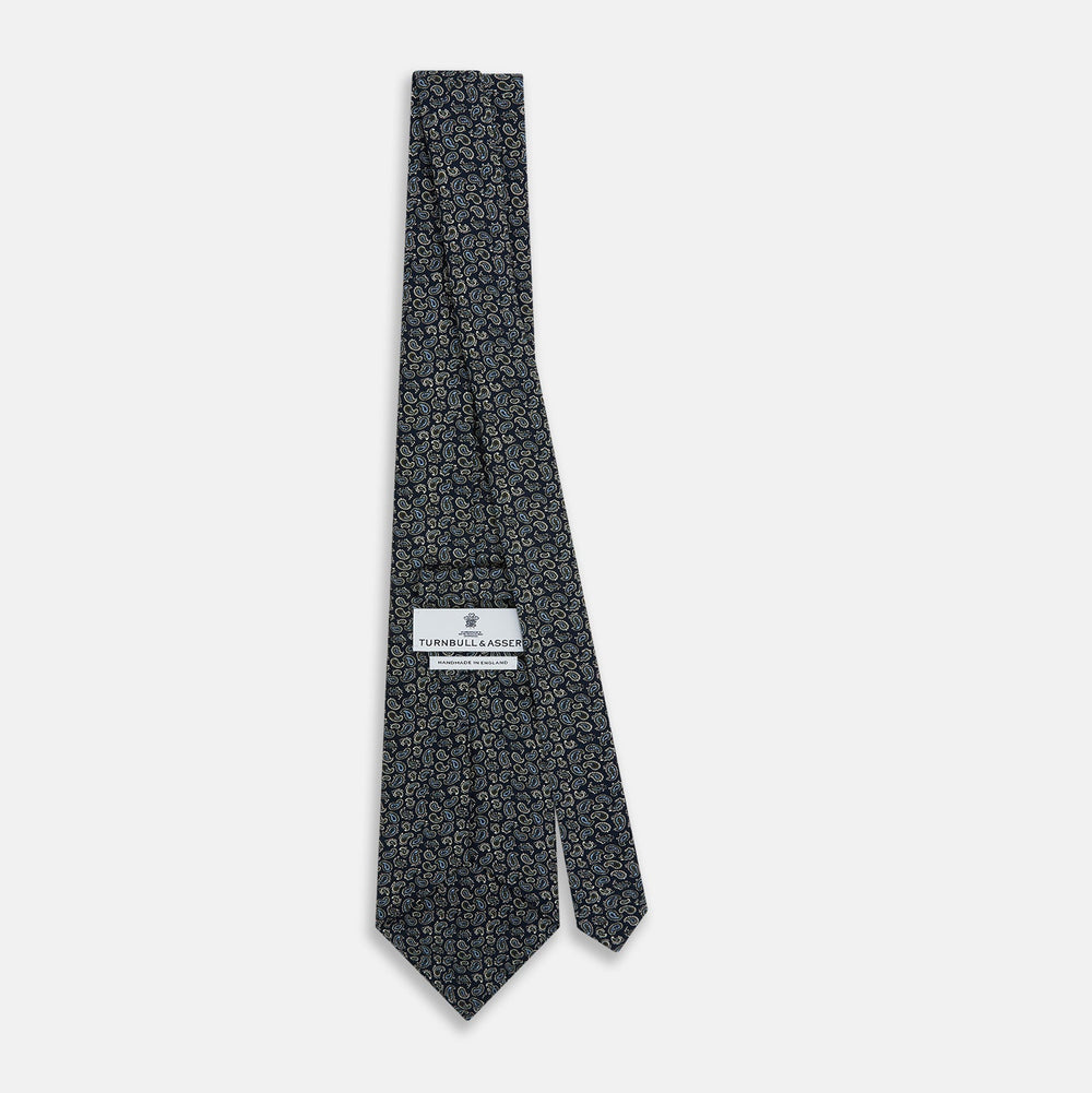 The Turnbull & Asser Navy Paisley Foulard Silk Tie features a refined paisley pattern in blue, white, and beige tones, elegantly rolled and presented against a white background.