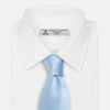 View 2 of product The Turnbull & Asser SATIN RIVER TIE, a neatly rolled light blue silk accessory with a smooth matte finish, is displayed against a plain white background.